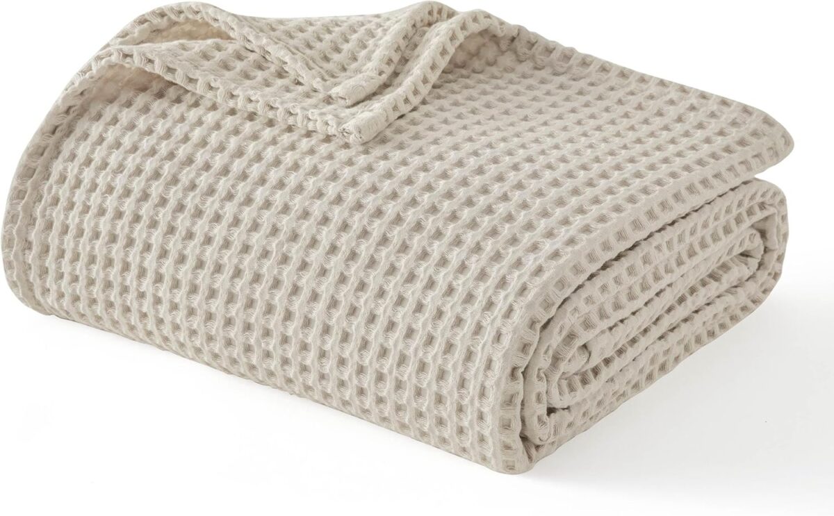 A folded beige waffle-knit blanket with a textured, grid-like pattern on a white background—perfect for cozy spaces or as inspiration in guides about the Best Tools for Faceless Businesses.