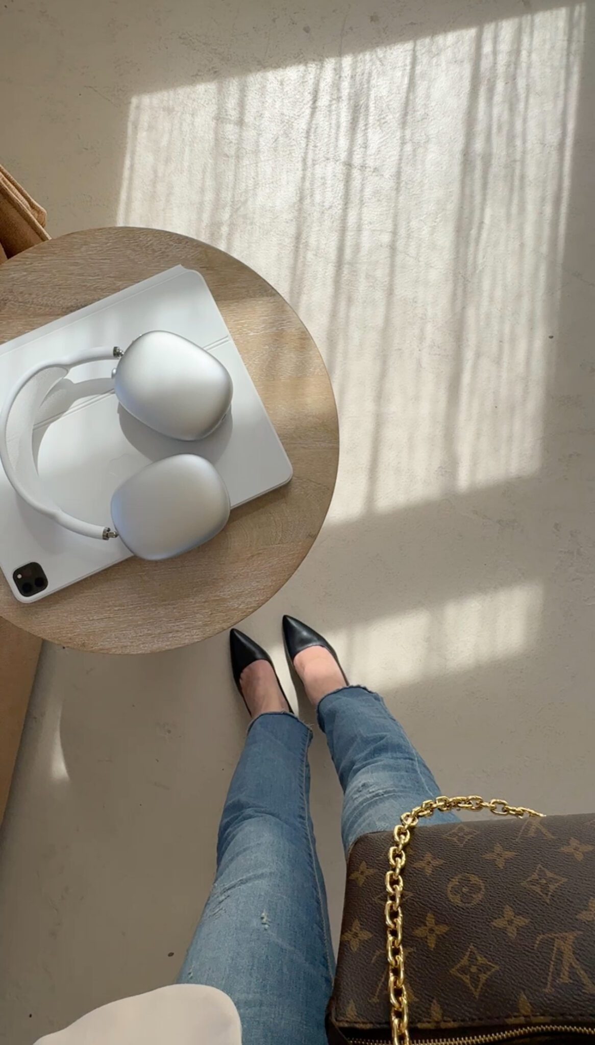 Overhead view of a table with headphones and laptop, person in jeans and heels holding a designer bag—perfect for Faceless Content Banks inspiration.