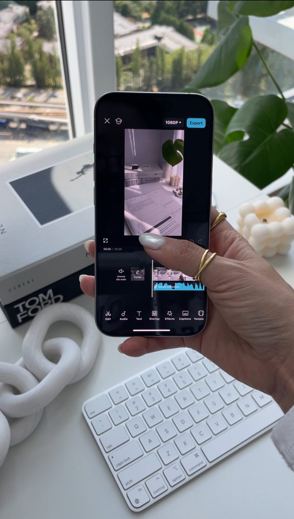 A person edits a video on a smartphone at a modern white desk with decor and a keyboard, creating visuals ideal for Faceless Content Banks.