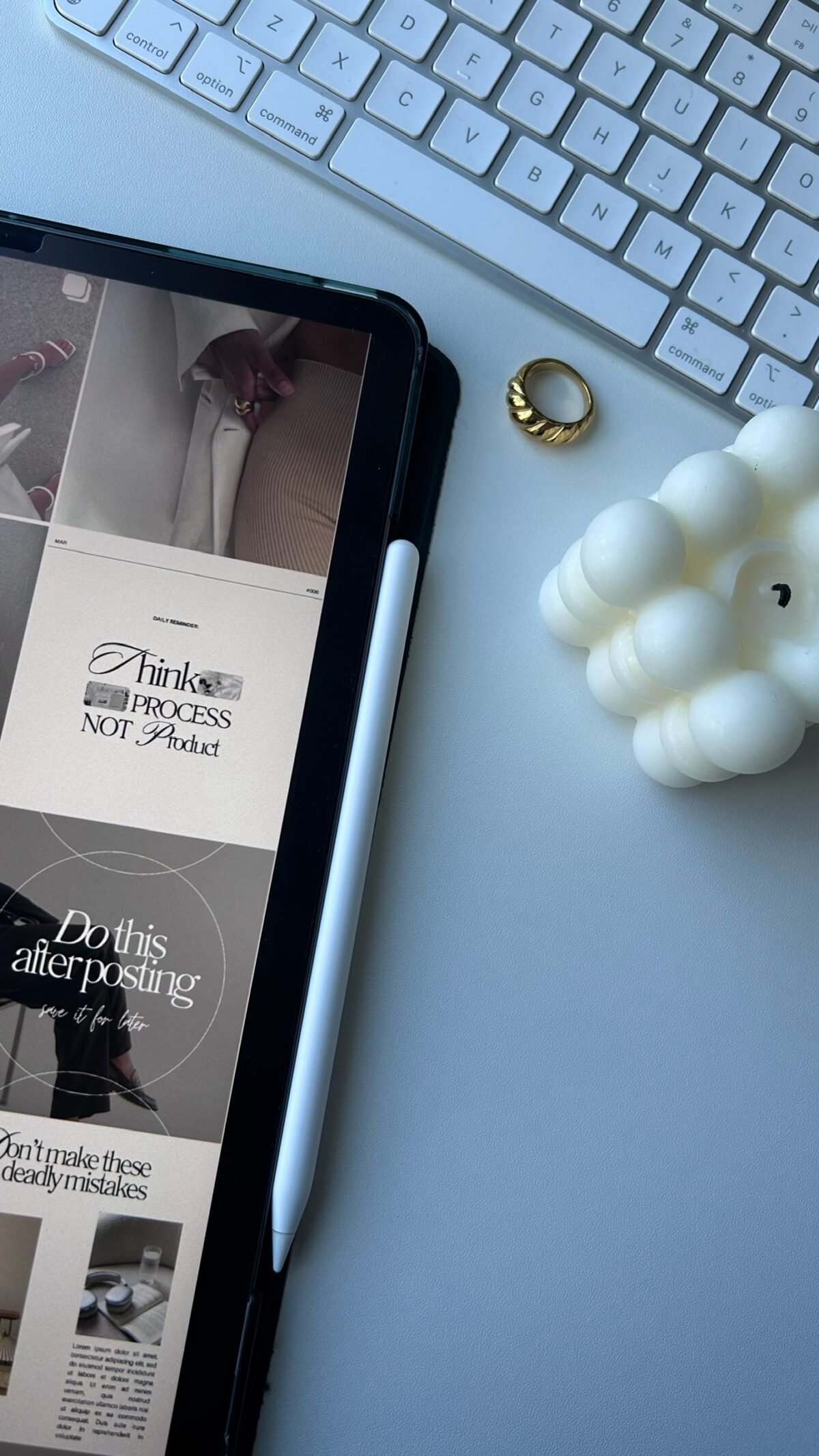 Tablet displaying Faceless Content Banks, alongside inspirational quotes, a white keyboard, gold ring, and bubble candle on a light gray desk.