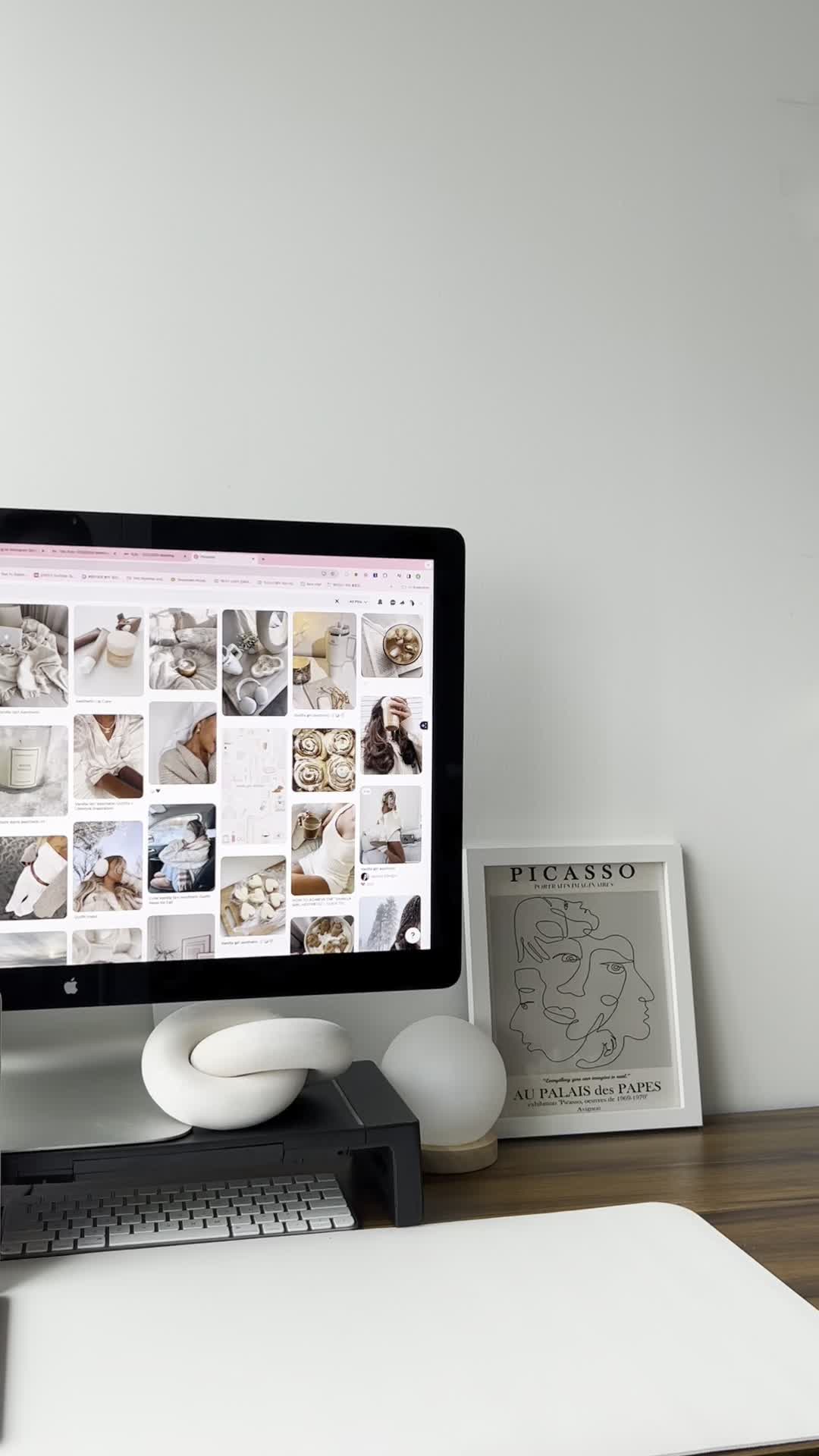 Minimalist workspace with a computer, framed Picasso print, and modern white desk decor—perfect for exploring how to start faceless digital marketing efficiently and creatively.